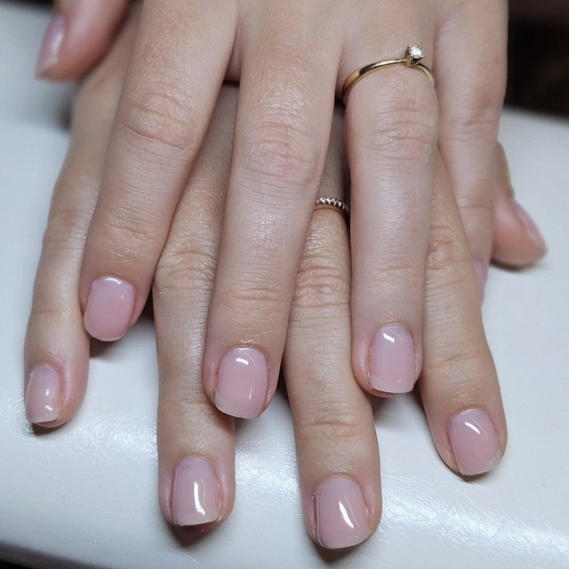 Korte, naturel roze nagels op een witte armsteun